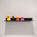 A black steel shelf in a modern bathroom design in Johannesburg. The modern bathroom shelf holds 4 rubber ducks in various colours.