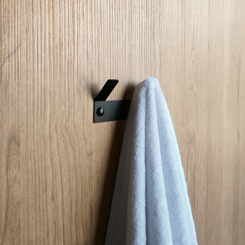 A black bathroom towel hook or a black wall hook hanging a white towel in a luxury bathroom store in johannesburg