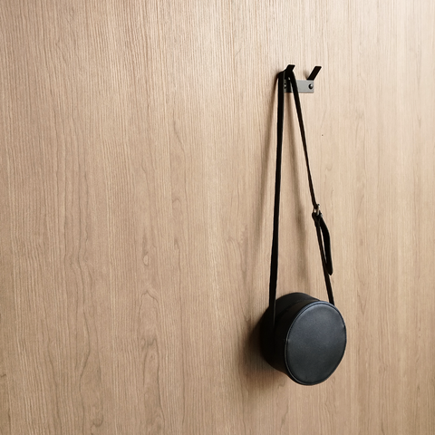 A black bathroom towel hook or a black wall hook or a handbag hook hanging a black handbag in a luxury design store in Johannesburg