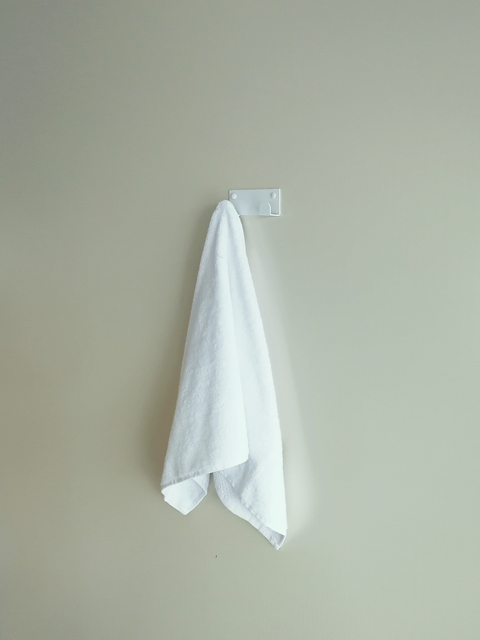 A towel hook in South Africa or a white wall hook is hanging a white bath towel in a bathroom design store in Johannesburg