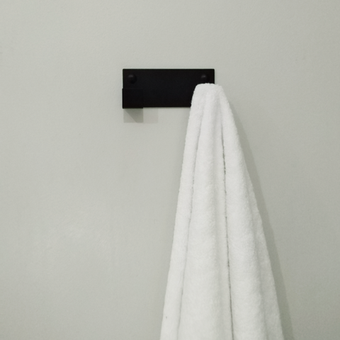 A black wall hook for hanging coats or a black towel hook is hanging a white bathrobe in a bathroom design store in Johannesburg 