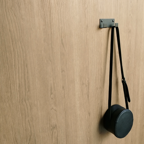 A black coat hook or black wall hook for hanging or a handbag hook is holding a black handbag in a bathroom design store in Joahnnesburg 