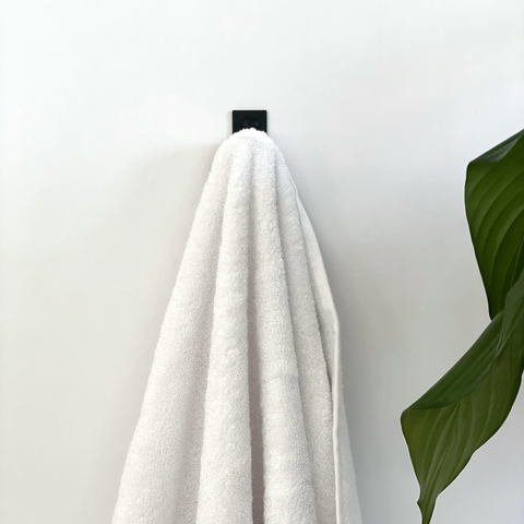 A black wall hook or a black towel hook in a ctm bathroom store in Johannesburg with a white towel and decor from Mr Price Home