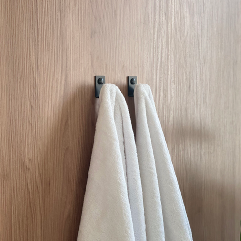 A double black towel hook or wall hook for hanging towels in a bathroom design store in Johannesburg. A white towel is hanging from the black coat hook